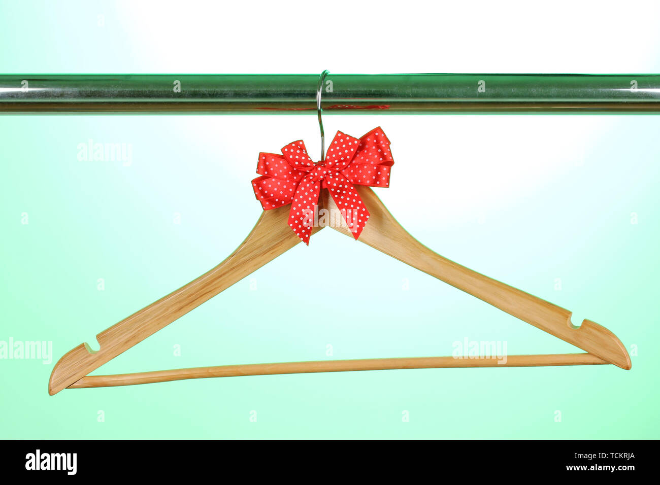 Beautiful red bow hanging on wooden hanger on green background Stock Photo