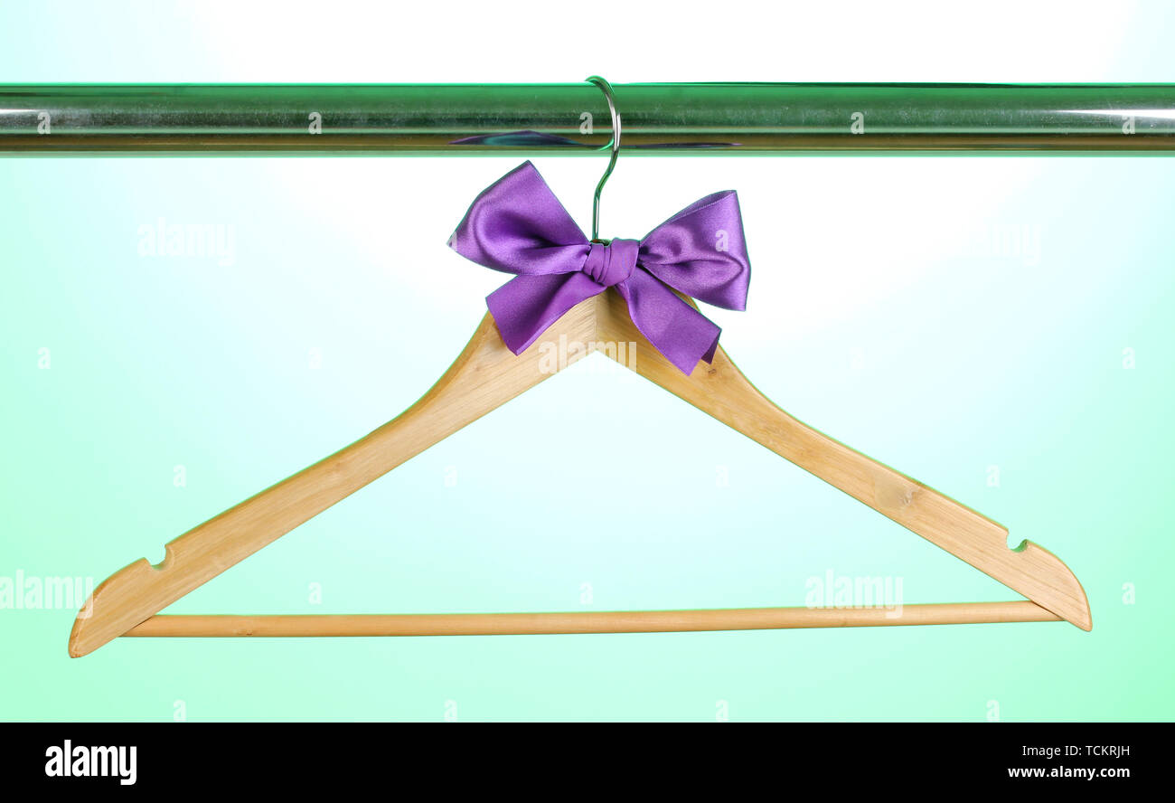 Beautiful purple bow hanging on wooden hanger on green background Stock Photo