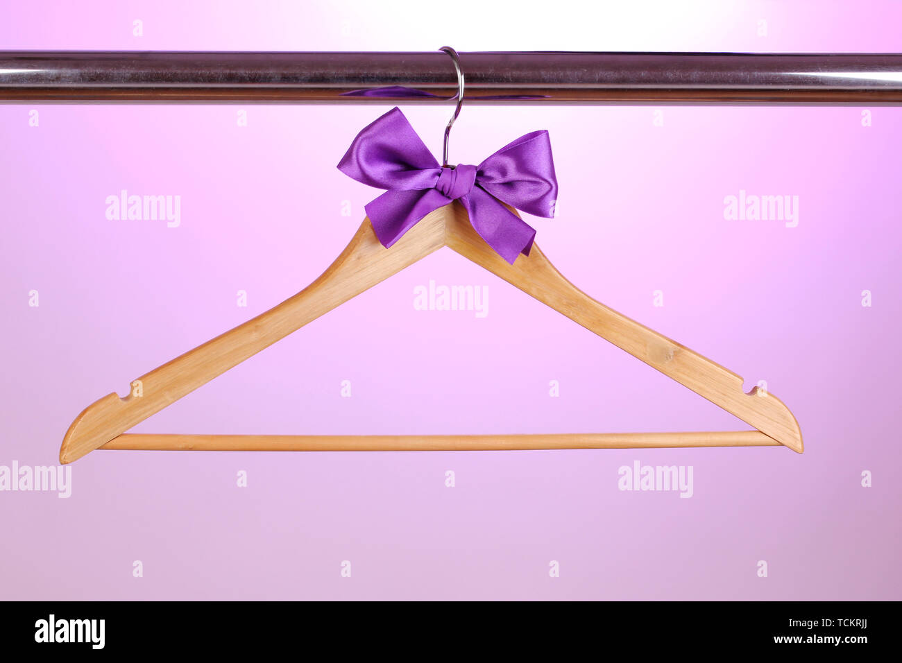 Beautiful purple bow hanging on wooden hanger on purple background Stock Photo
