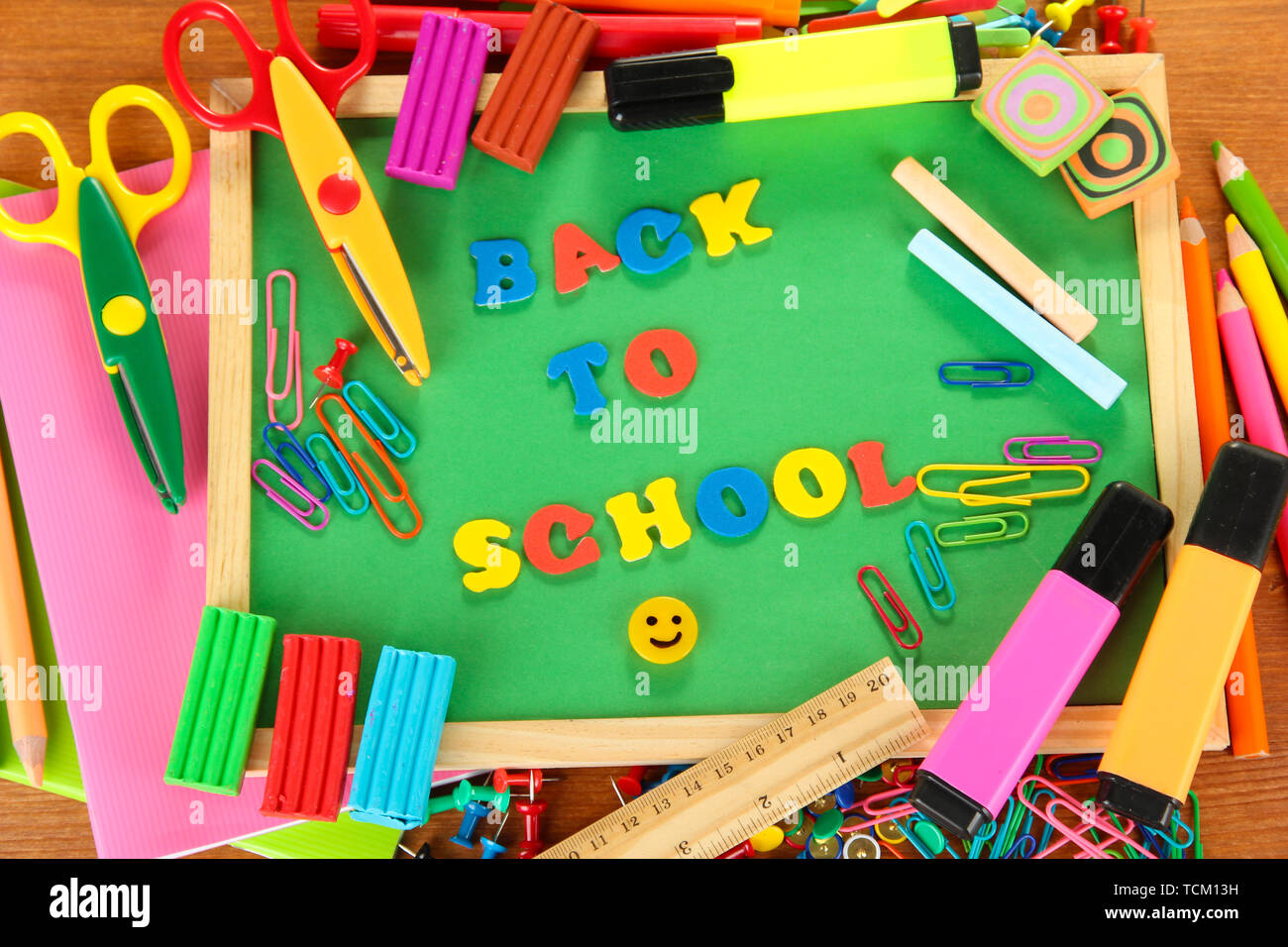 Small chalkboard with school supplies on wooden background. Back to
