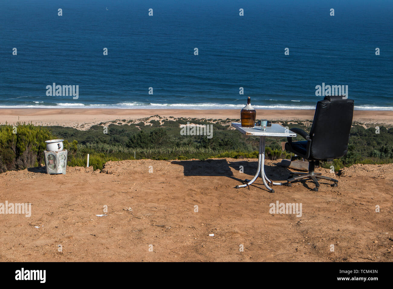 Ocean View with chair wine bottle and potty overlooking a great seaview Portugal. Someone with a sense of humour placed these items on a piece of land Stock Photo