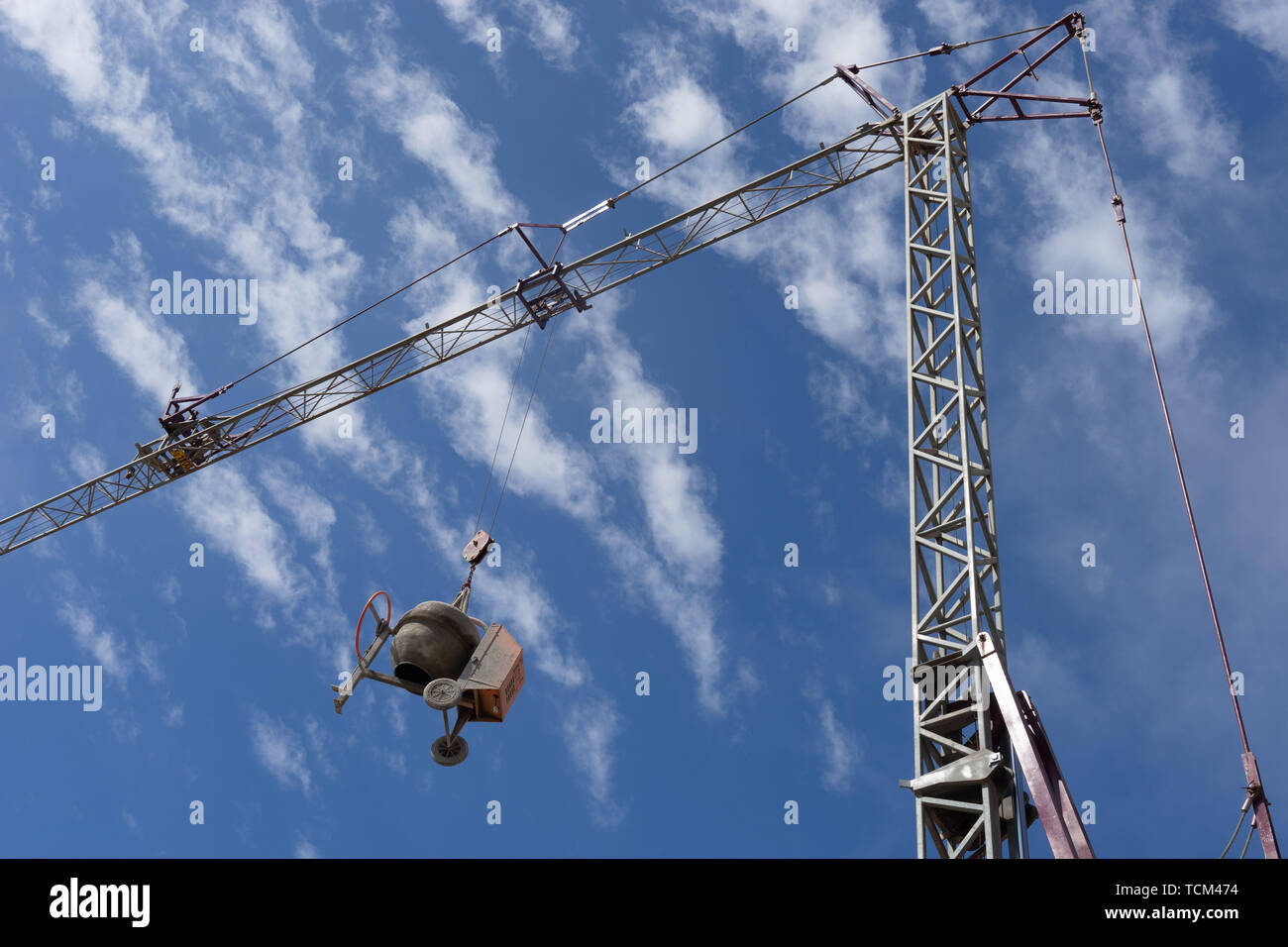 Concrete mixer suspended in the air by a tower crane, preventing the construction equipment from being stolen Stock Photo