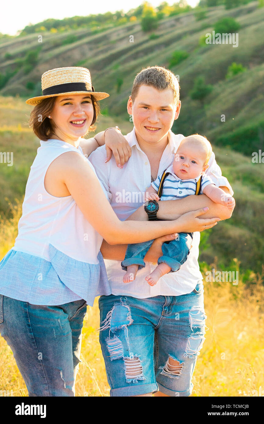 Happy family with little baby spending time together at sunset, on summer or autumn day, warm sunlight Stock Photo