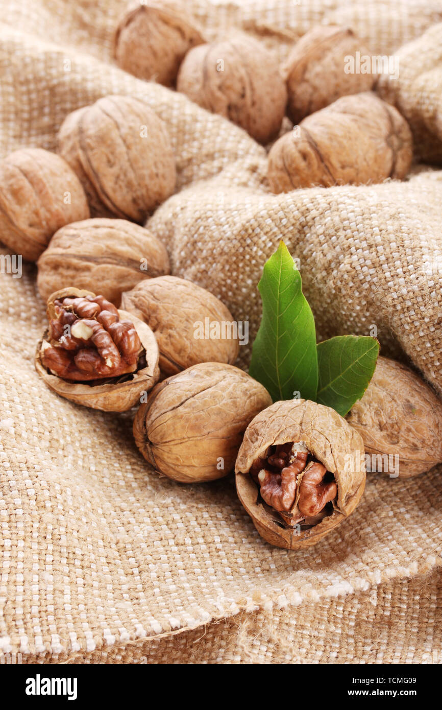 walnuts with green leaves, on burlap background Stock Photo