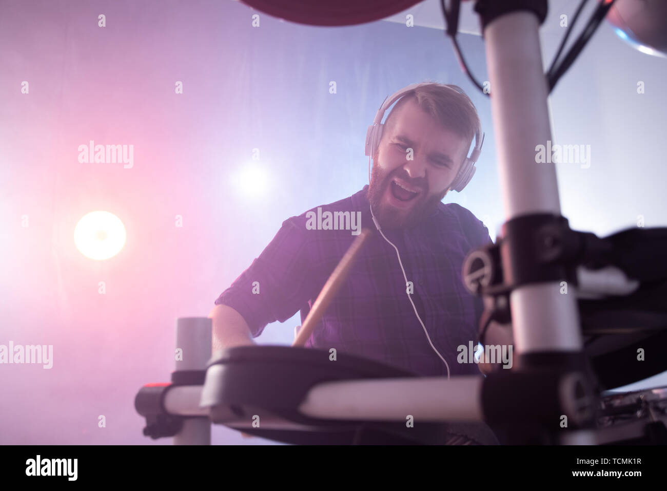 People, music and hobby concept - emotional man playing electronic drums on the stage Stock Photo