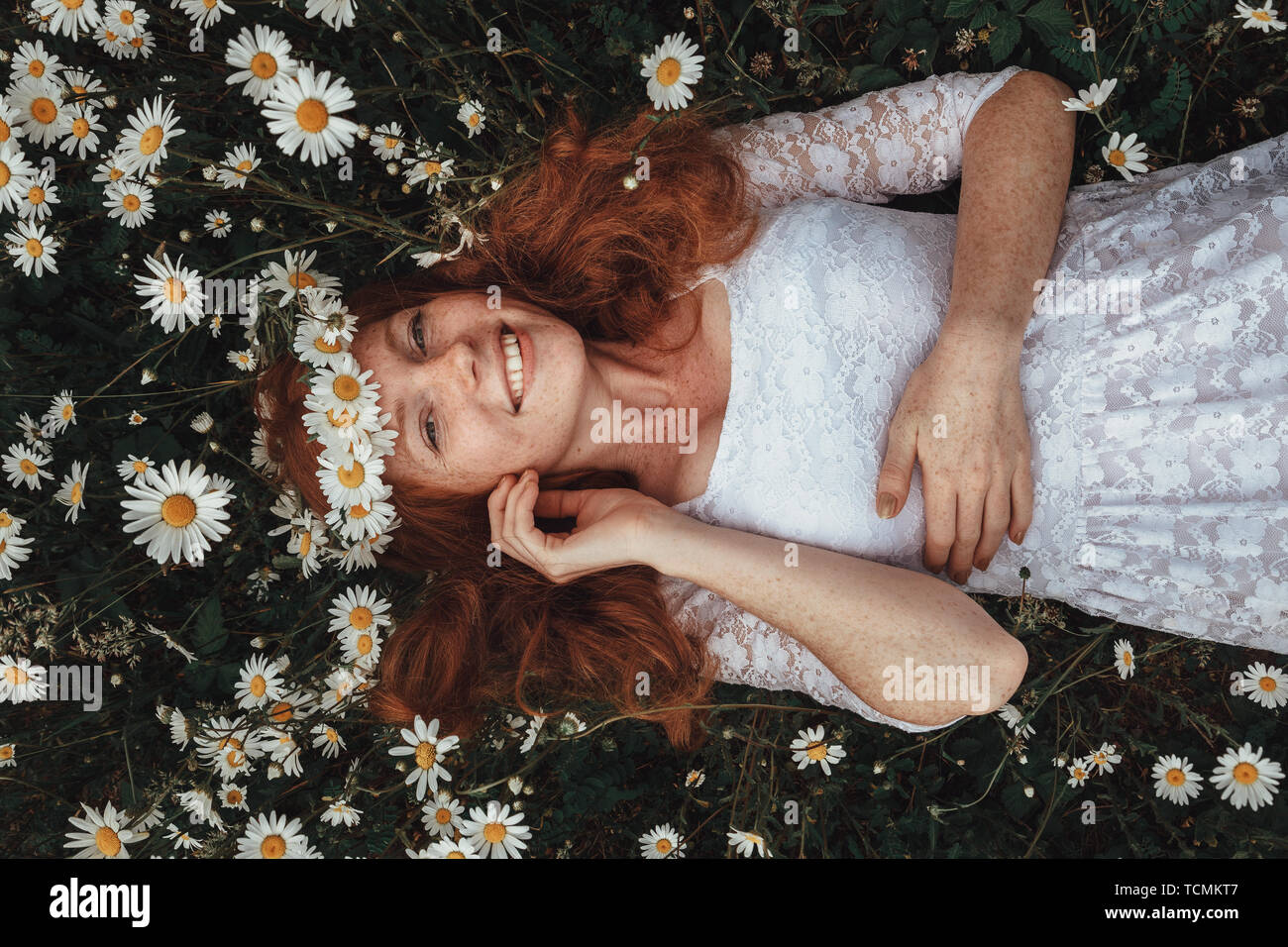 Beautiful young girl with curly red hair in chamomile field Stock Photo ...