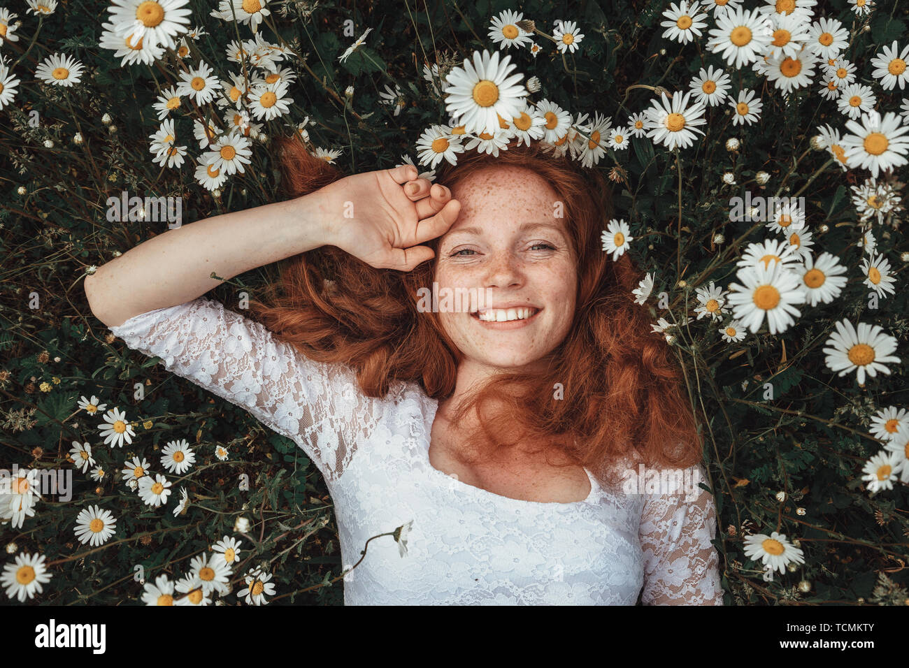 Beautiful young girl with curly red hair in chamomile field Stock Photo ...
