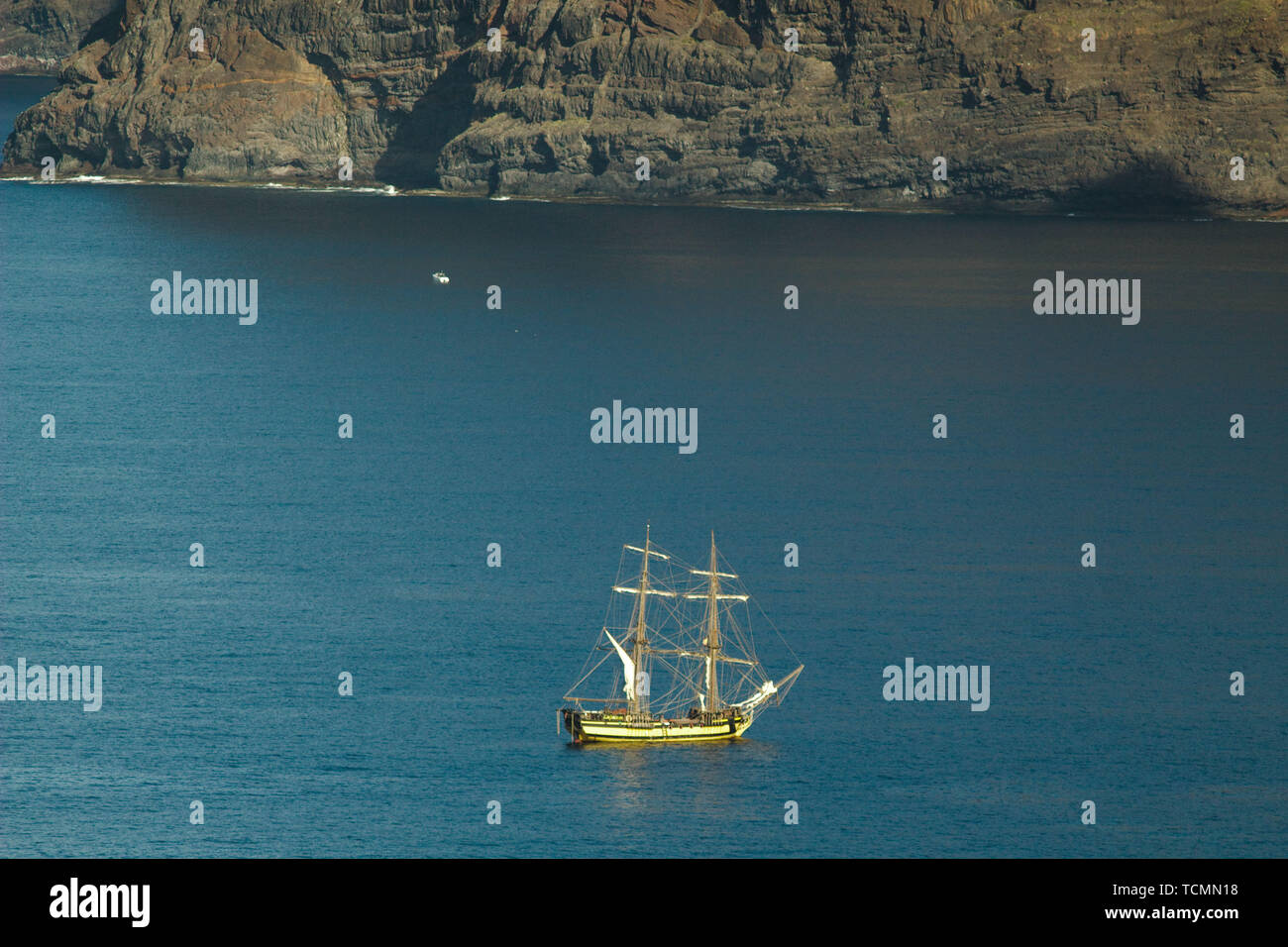 Yacht of tourists near the vertical cliffs Acantilados de Los Gigantes (Cliffs of the Giants). View from Atlantic Ocean. Stock Photo