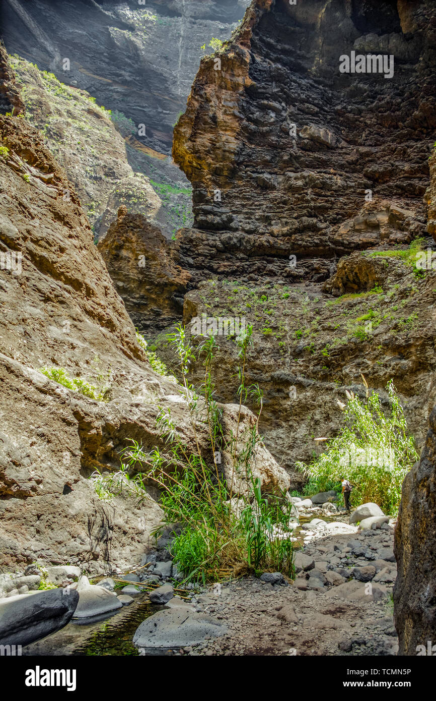 Rocks in the Masca gorge, Tenerife, showing solidified volcanic lava flow layers and arch formation. The ravine or barranco leads down to the ocean fr Stock Photo