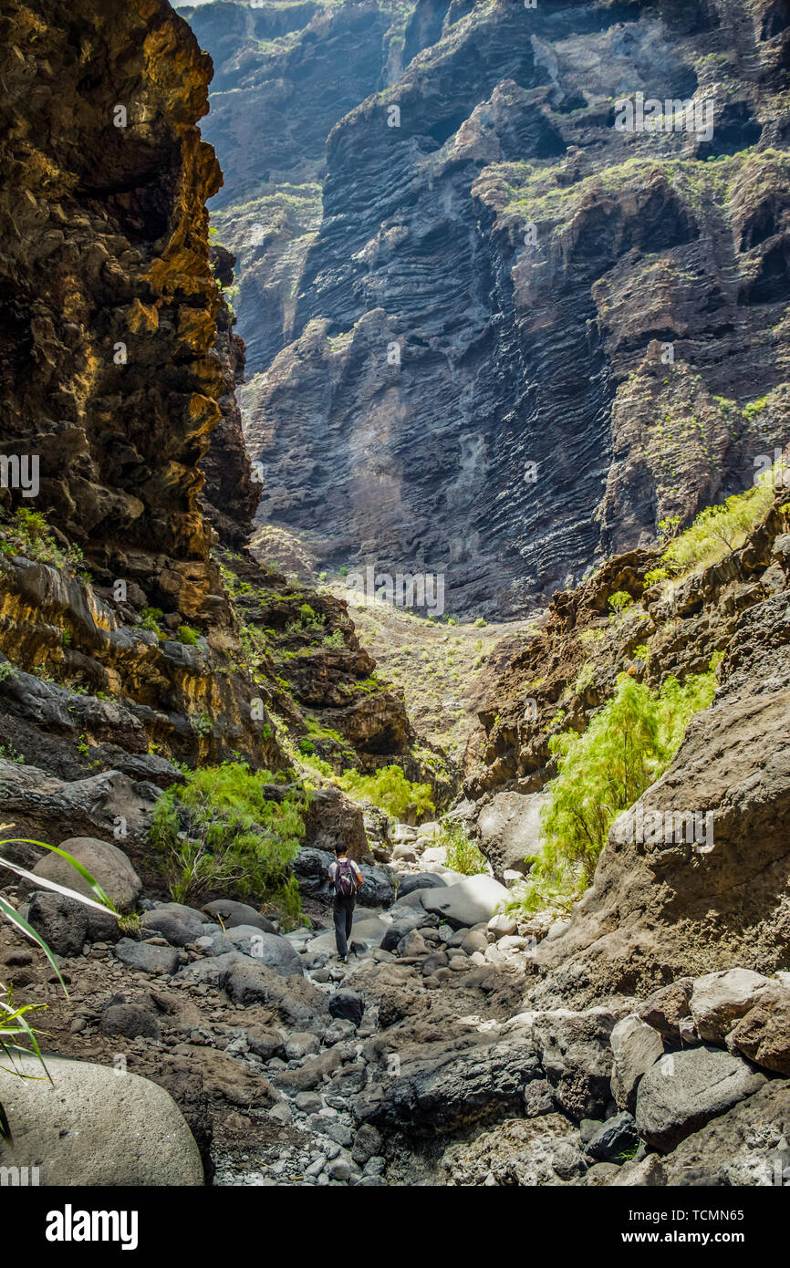 Rocks in the Masca gorge, Tenerife, showing solidified volcanic lava flow layers and arch formation. The ravine or barranco leads down to the ocean fr Stock Photo