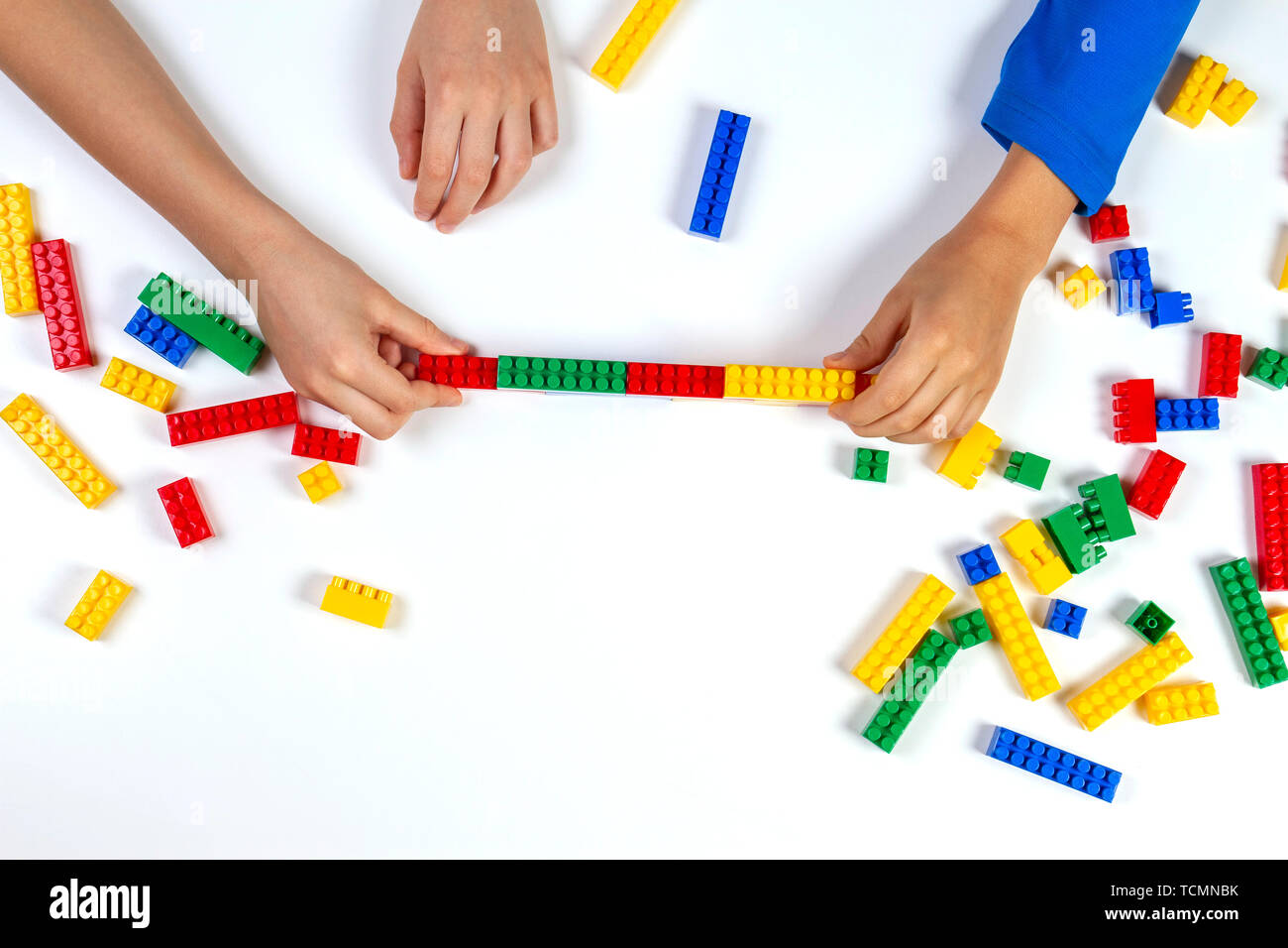 Kids hands playing with colorful building plastic bricks on white ...