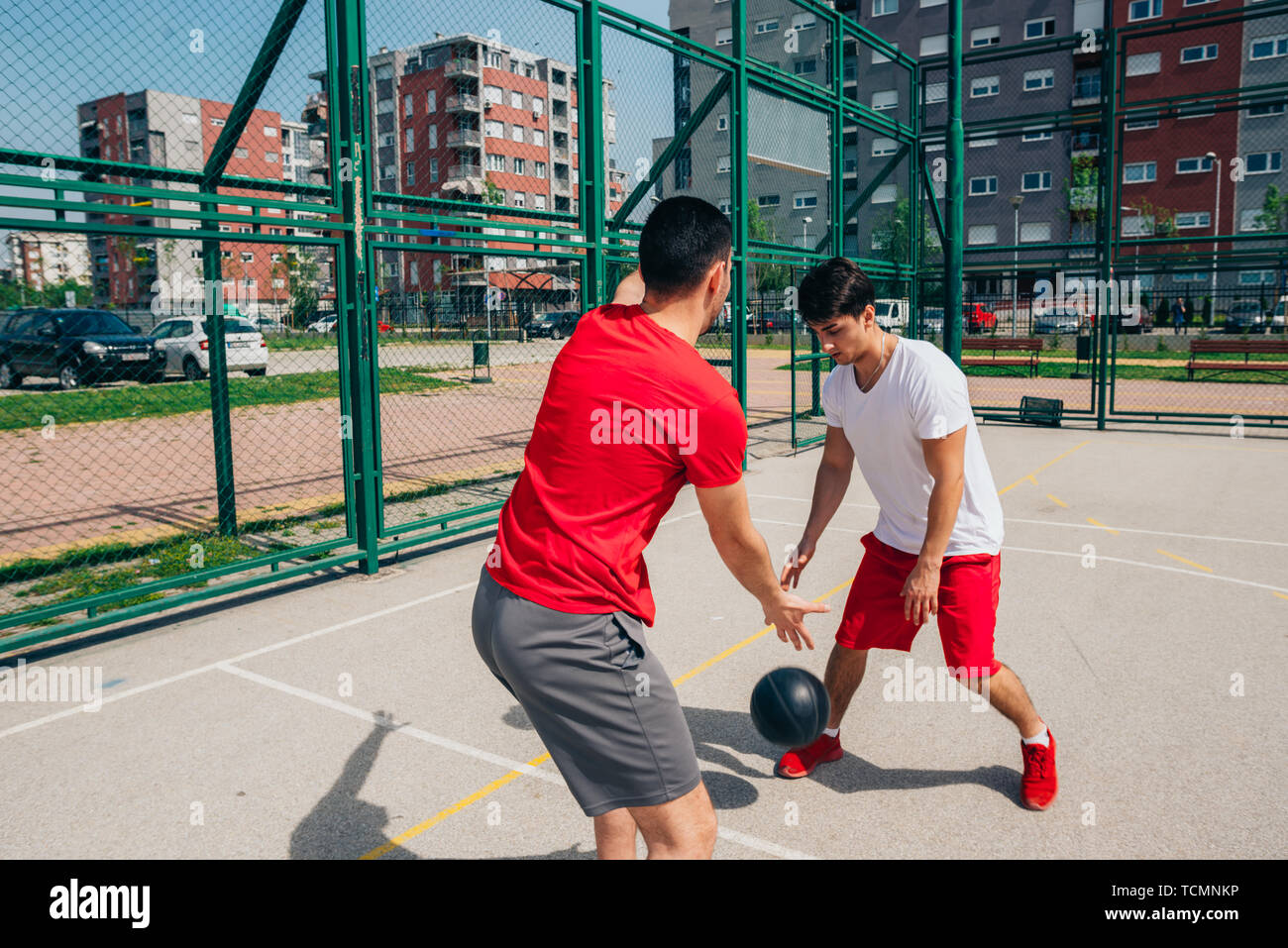 Two strong male basketball players play ball out doors fighting for a