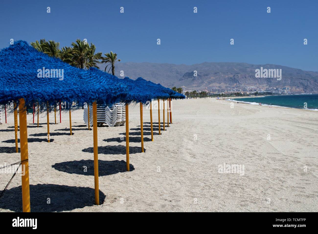 Sun umbrellas and sunbeds in the sand on the shore of the mediterranean ...