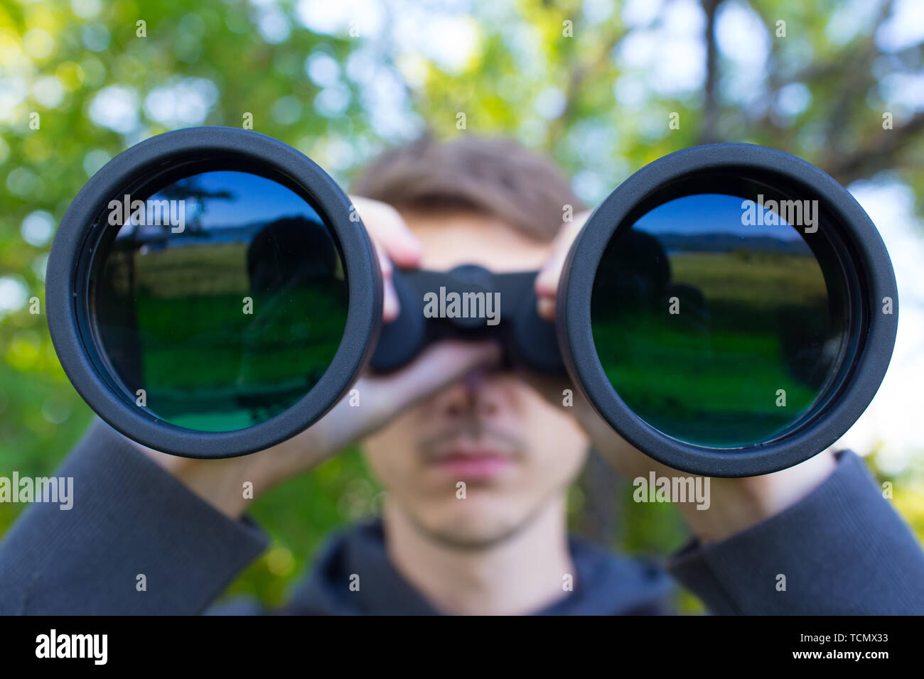 Young Man use of the binocular at forest. Tourist Camping Stock Photo