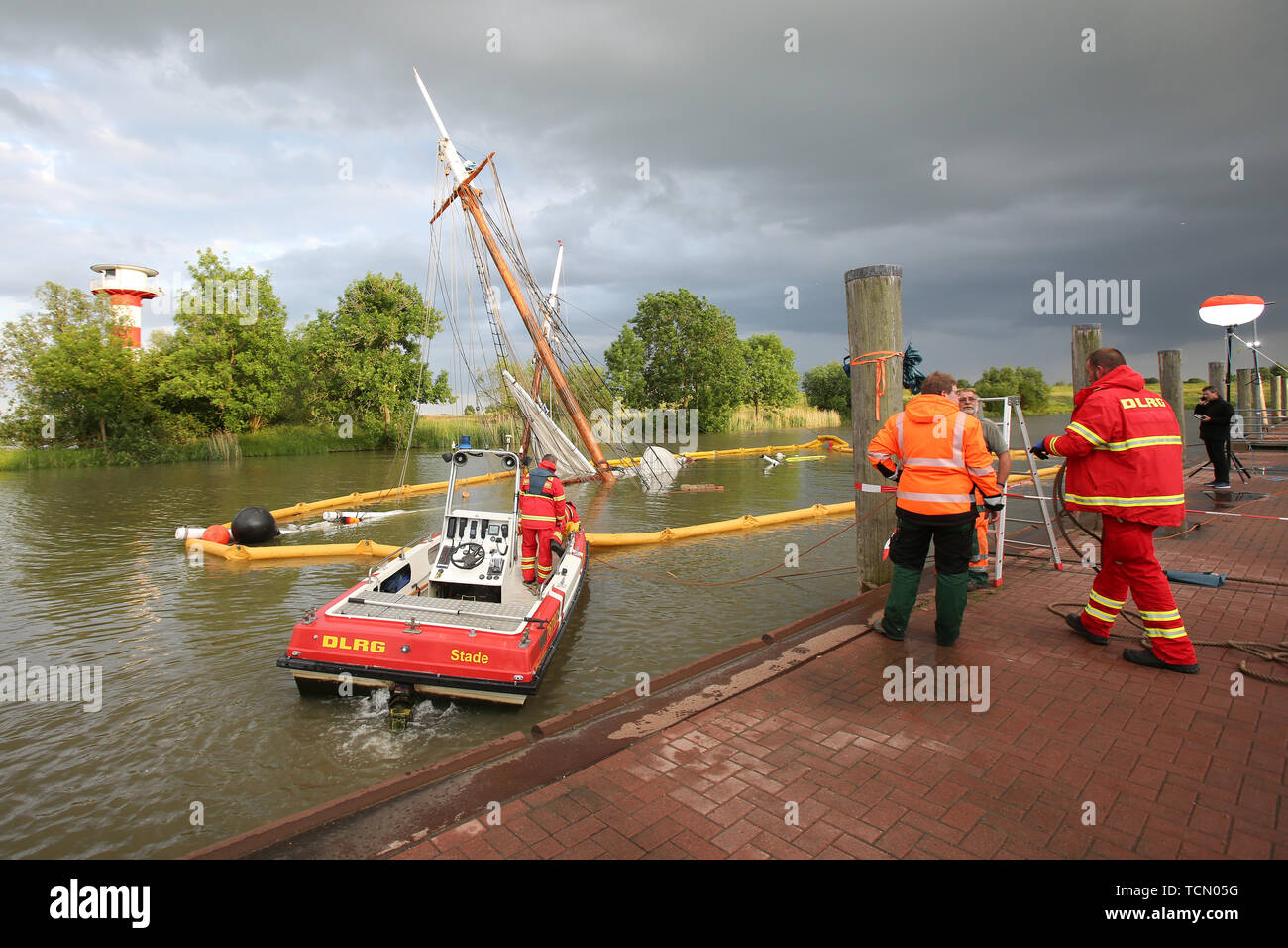Stadersand, Germany. 08th June, 2019. The sunken historic sailing ship 'No 5 Elbe' is almost completely under water in the harbour of Stadersand, while DLRG employees are in the process of securing an oil barrier. The historical sailing ship, which has only recently been extensively renovated, collided with a container ship on the Elbe and sank. Five people were injured in the accident in Stade on Saturday, one of them a woman, according to the Hamburg police. Credit: Bodo Marks/dpa/Alamy Live News Stock Photo