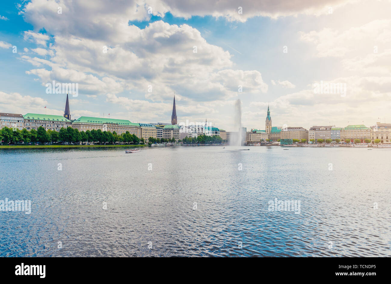 Hamburg cityscape on sunny day against blue sky with Alster lake and fountain in foreground Stock Photo