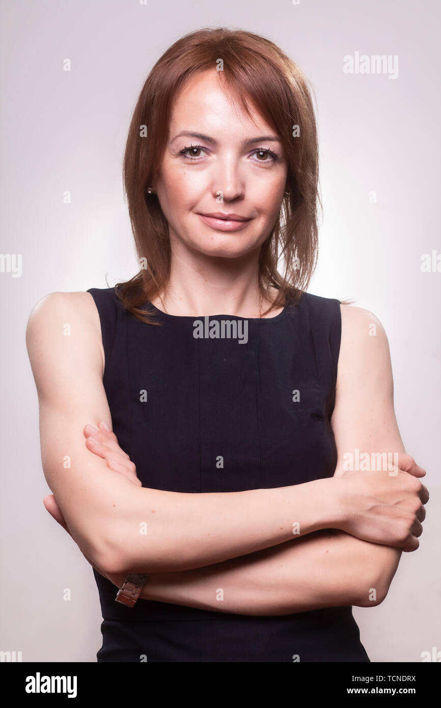 one beautiful mature woman portrait, content face expression, 40-49 years old, with her arms crossed. Looking at camera. Upper body shot, wearing a si Stock Photo