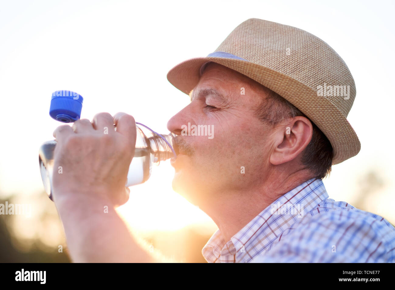 Senior hispanic man in summer hatdrinking fresh water Stock Photo