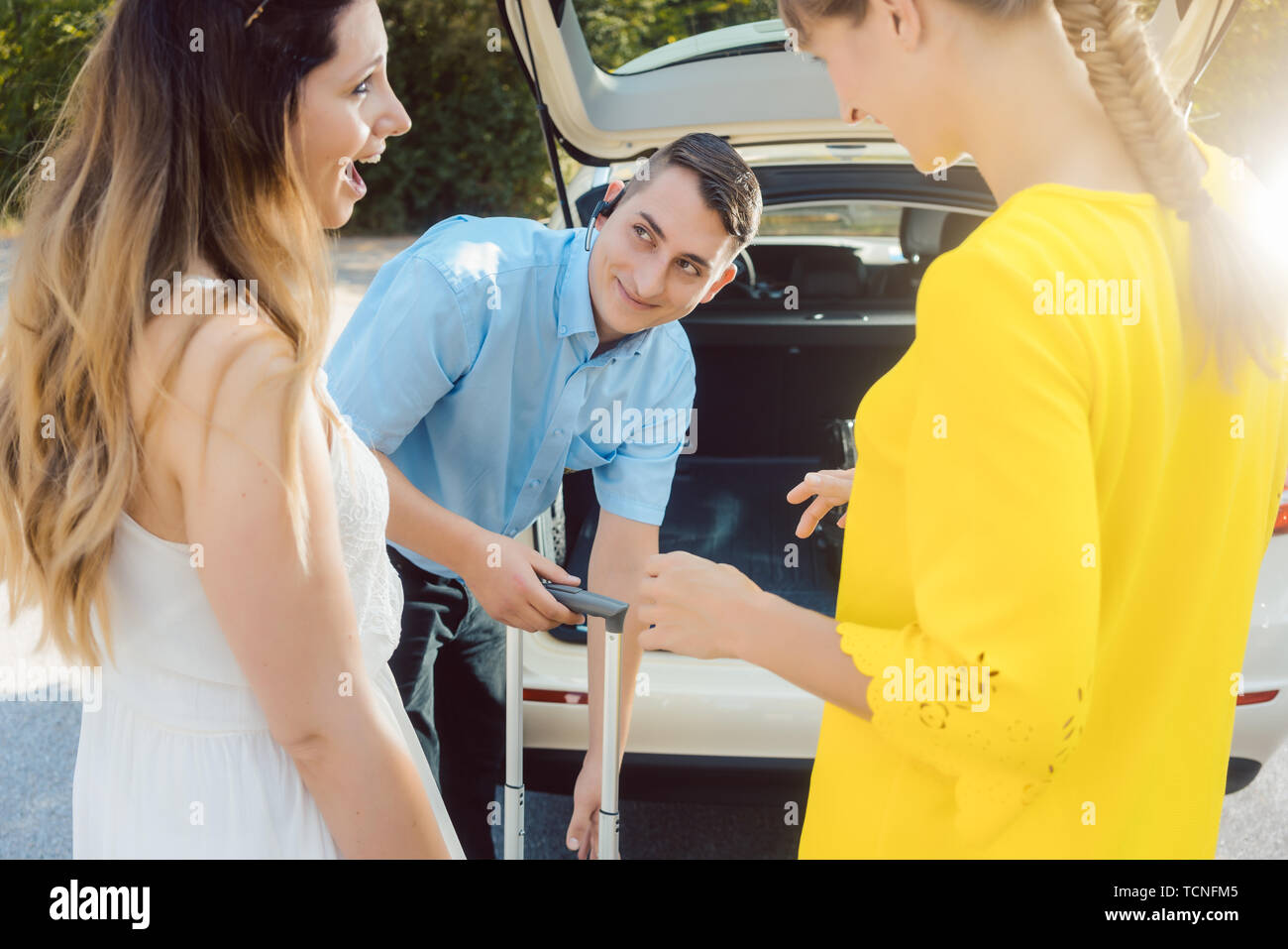 Taxi driver putting luggage of women in trunk of car getting ready to ...