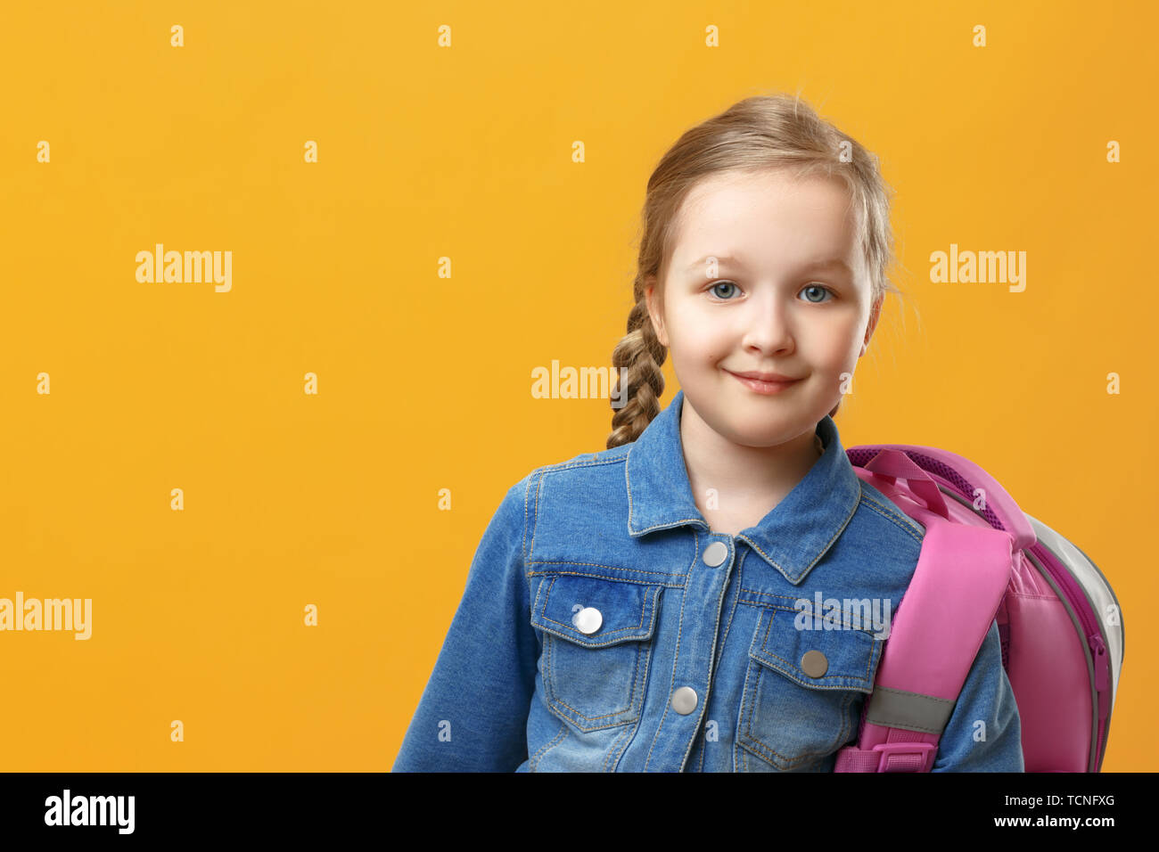 Portrait of a little girl schoolgirl with a backpack on a yellow background. Back to school. The concept of education. Copy space. Stock Photo
