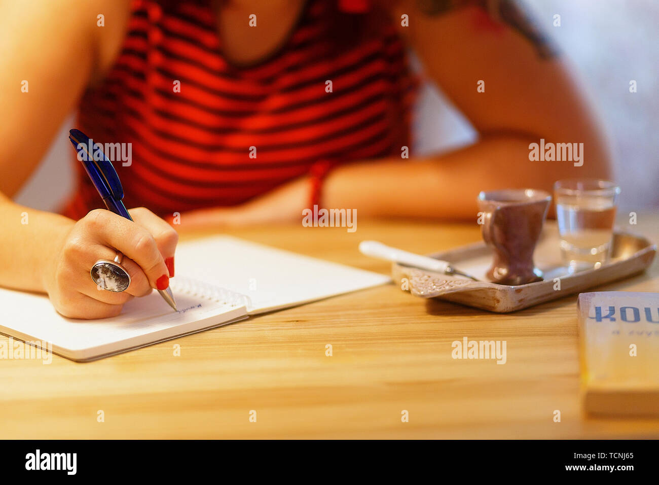 Close Up Of Lady S Hand Writing In Notepad In Coofee Bar Stock