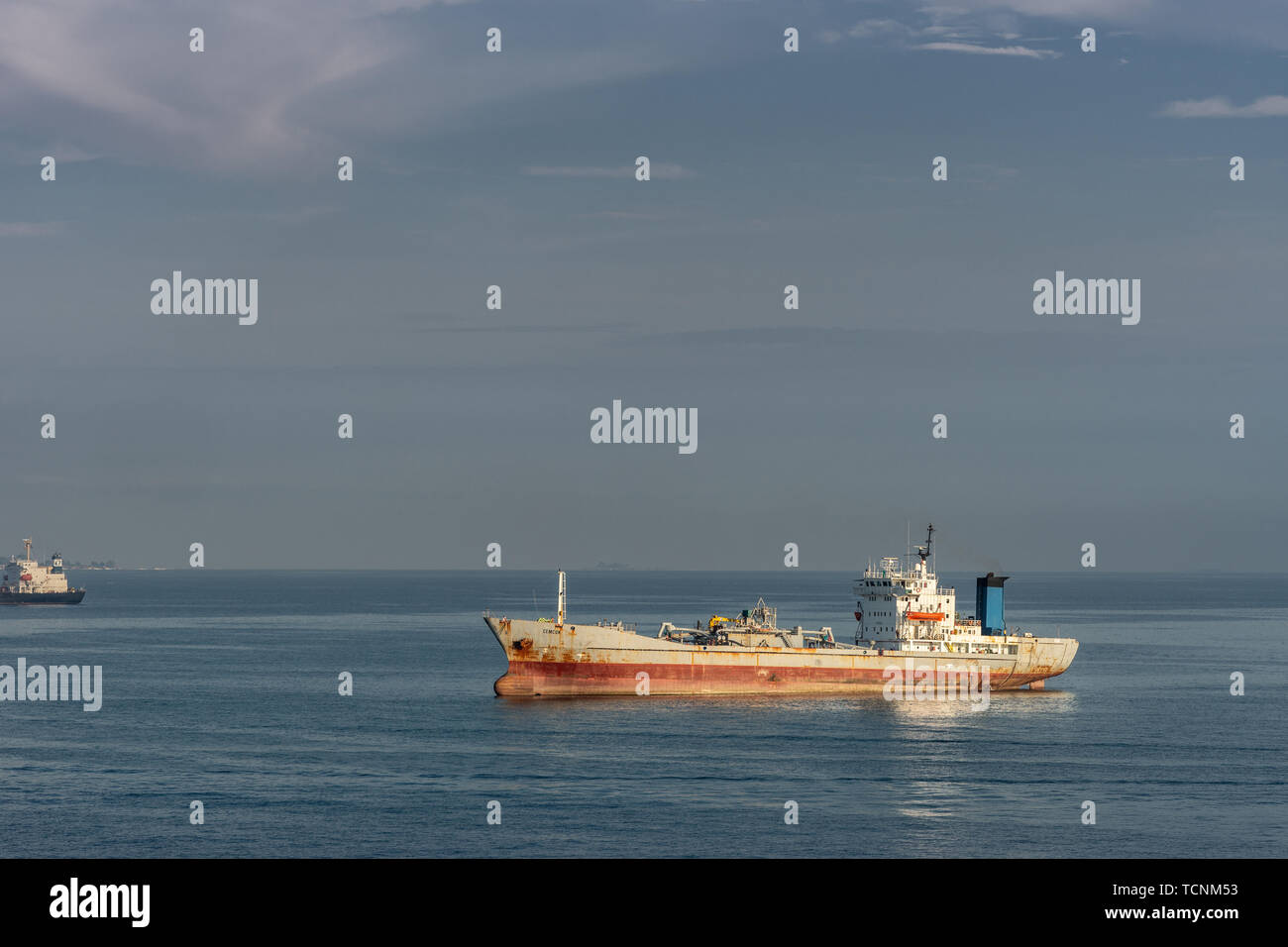 Makassar, Sulawesi, Indonesia - February 28, 2019: Rusty cement carrier Cemcon ship sails near port. Blue sea and sky. Stock Photo