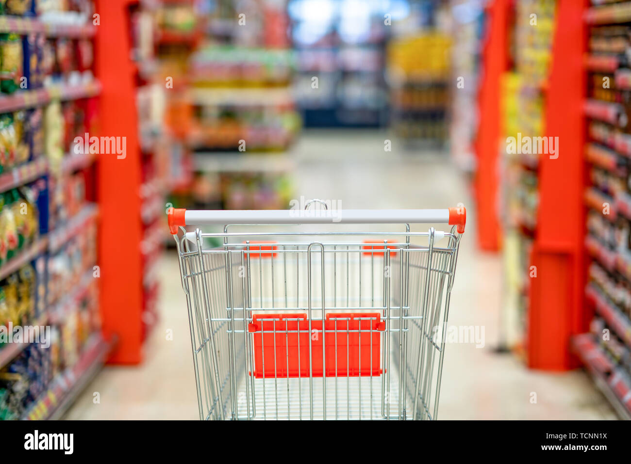 Empty shopping cart with blur supermarket  store aisle and product shelves interior background Stock Photo
