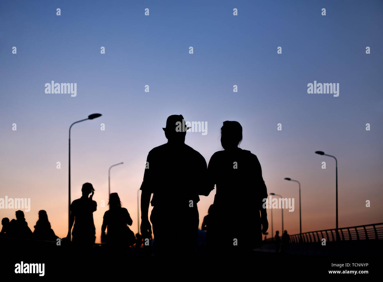 silhouette of couple man and woman walking on sunset on city road view ...