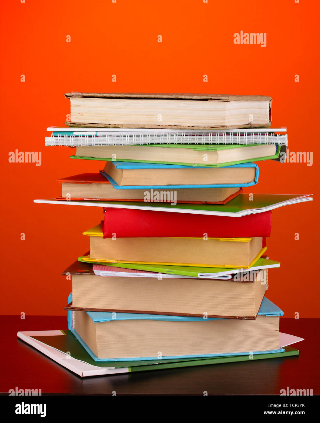 Stack of interesting books and magazines on wooden table on red ...