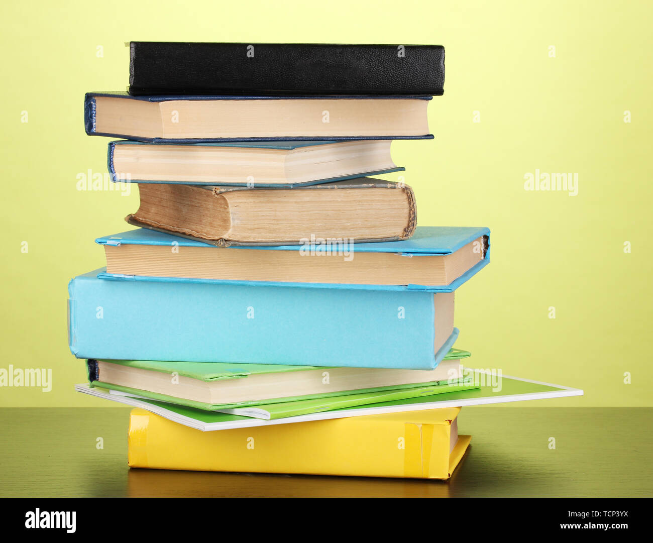 Stack of interesting books and magazines on wooden table on green ...