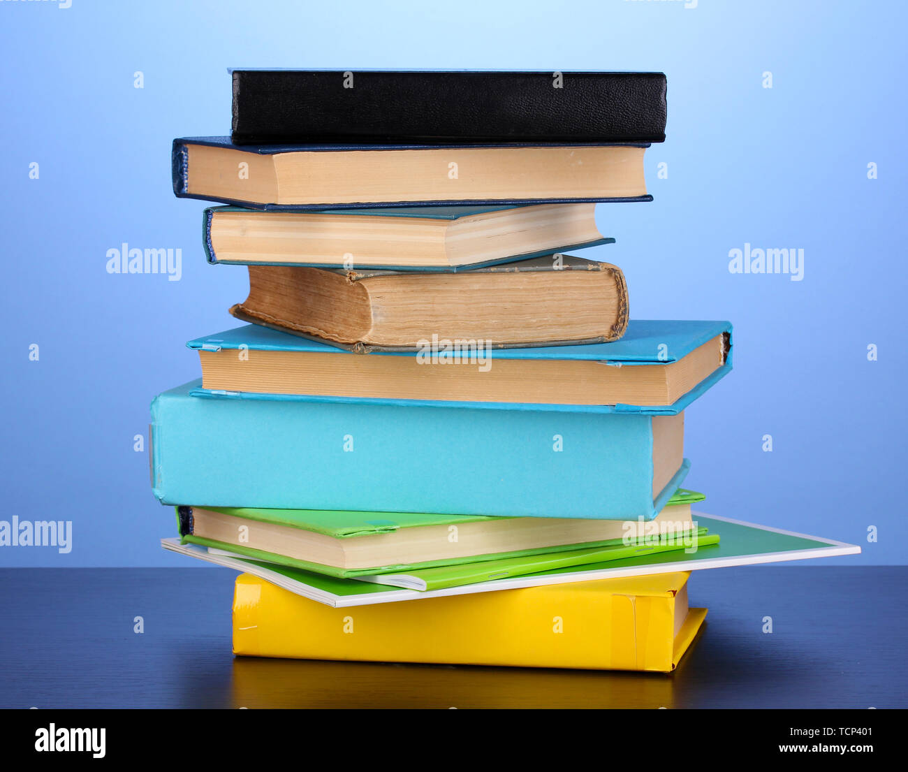 Stack of interesting books and magazines on wooden table on blue ...