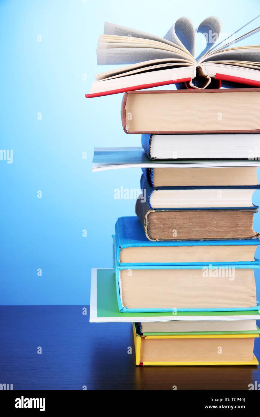 Stack of interesting books and magazines on wooden table on blue background Stock Photo