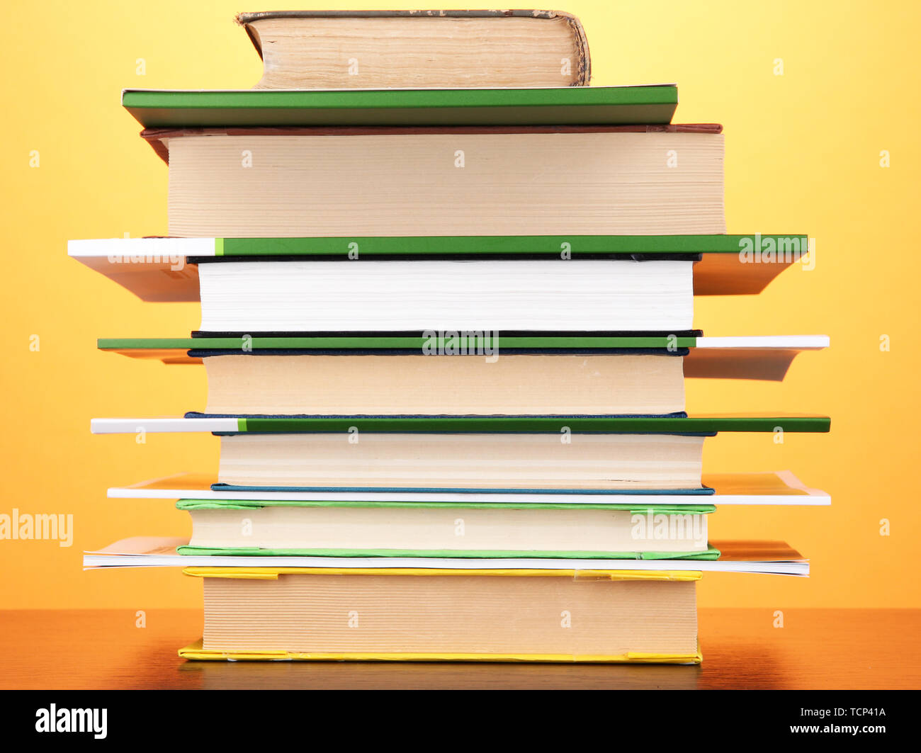 Stack of interesting books and magazines on wooden table on orange background Stock Photo