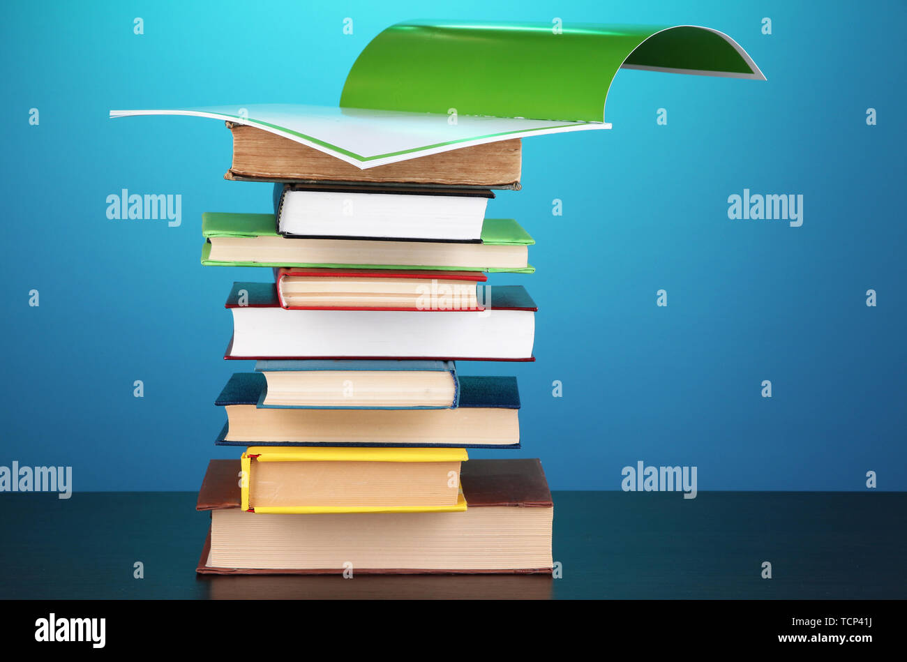 Stack of interesting books and magazines on wooden table on blue ...