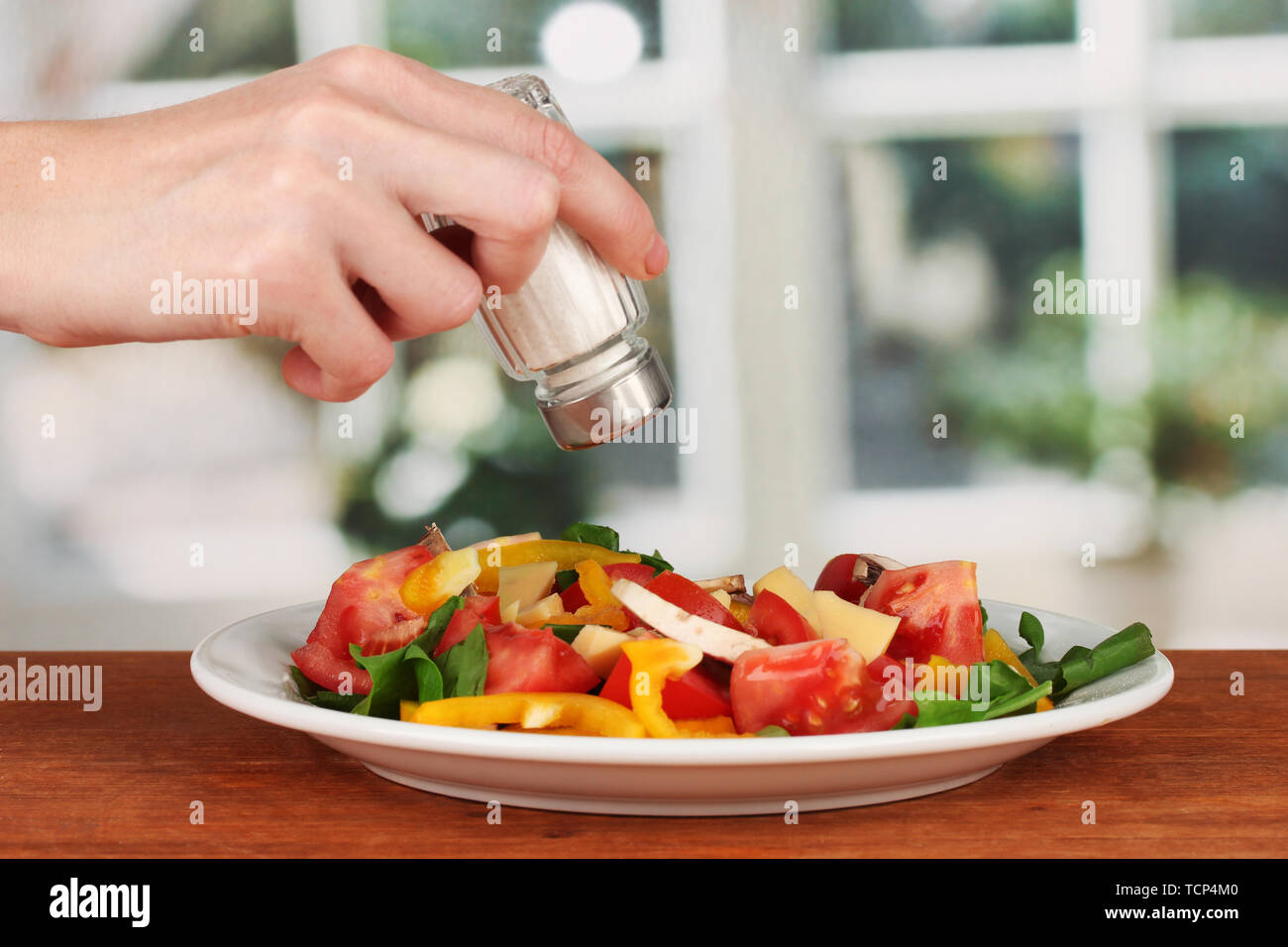 Hand adding salt using salt shaker on bright background Stock Photo - Alamy