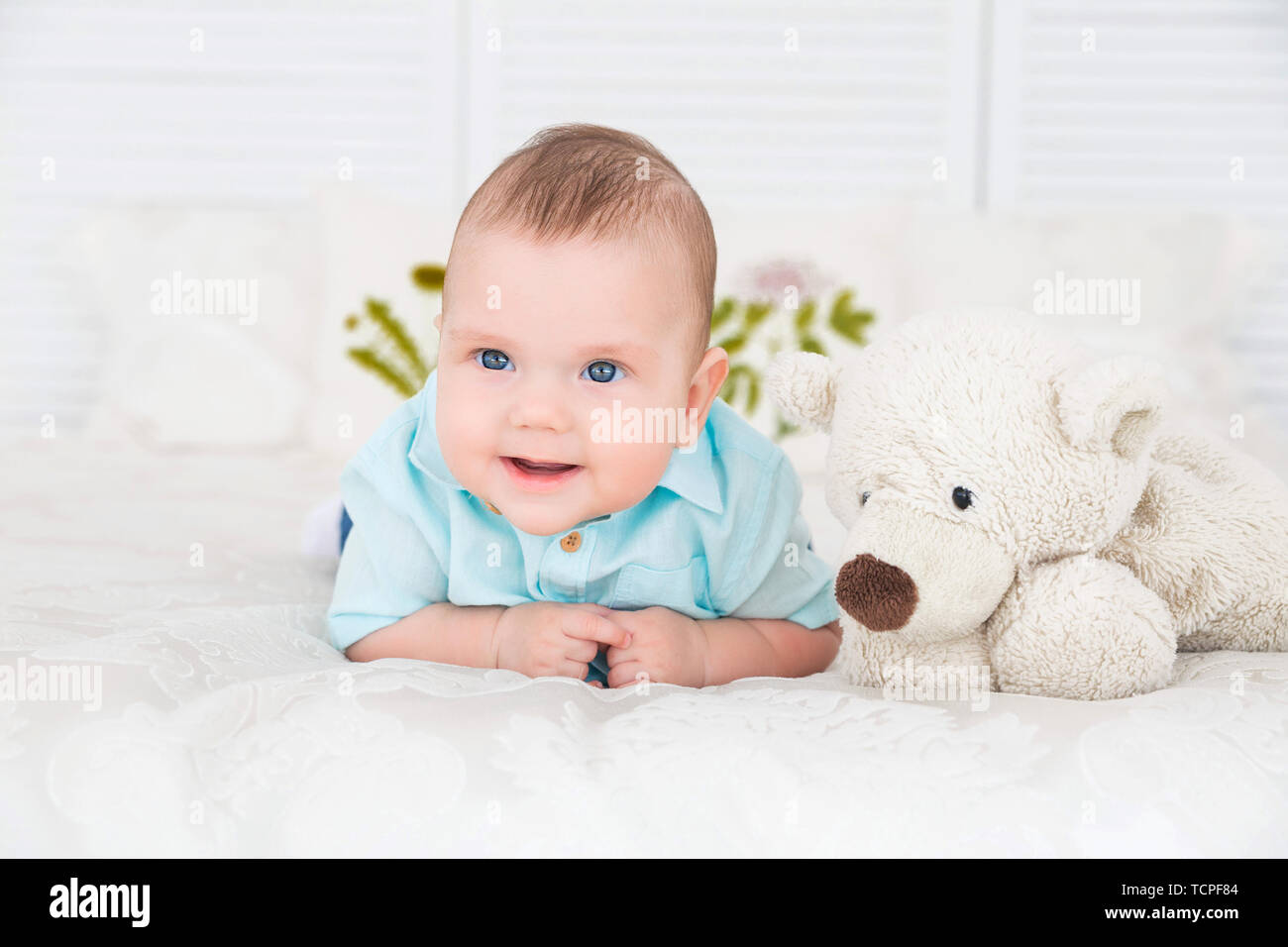 photo of little boy is lying on the bed next to a teddy bear Stock ...