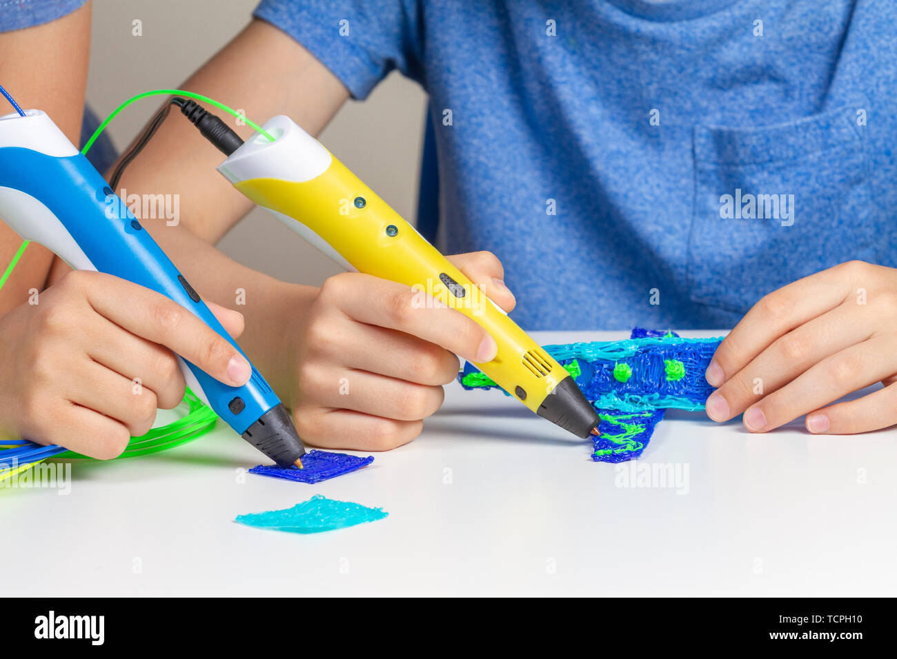 Two kid hands creating with 3d printing pens Stock Photo - Alamy