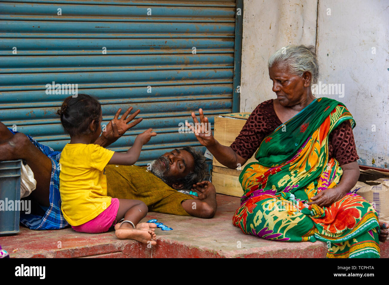 Poverty in Chennai, India, where three generations of a family play a game together Stock Photo