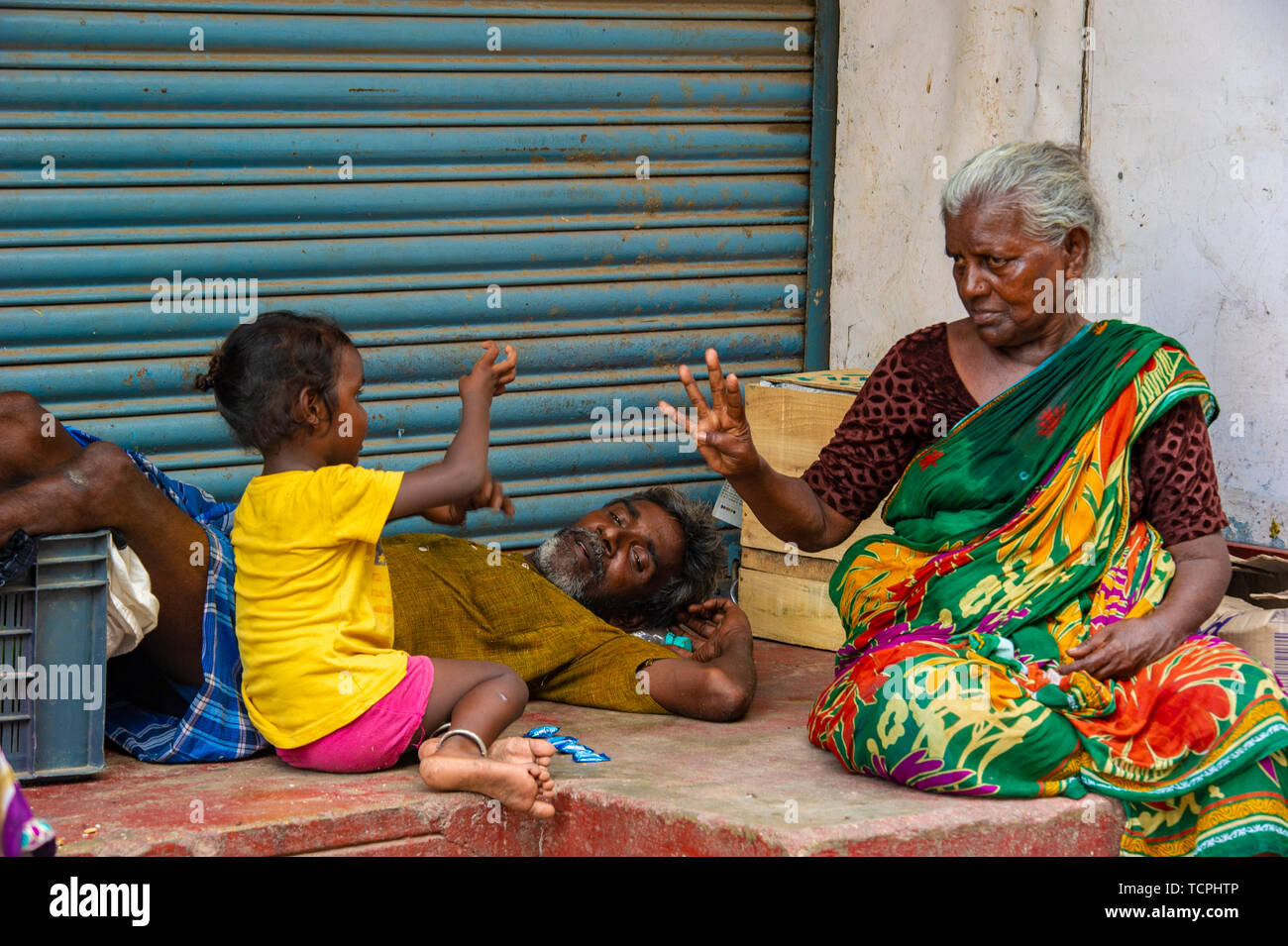 Poverty in Chennai, India, where three generations of a family play a game together Stock Photo