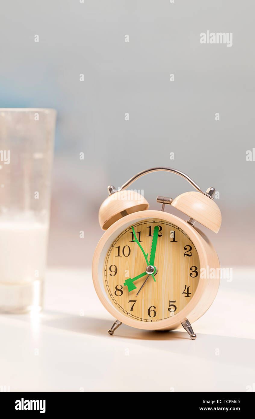 Milk and alarm clock on the table Stock Photo