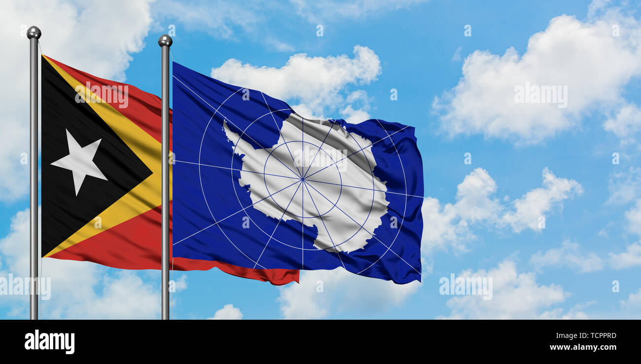 East Timor and Antarctica flag waving in the wind against white cloudy ...