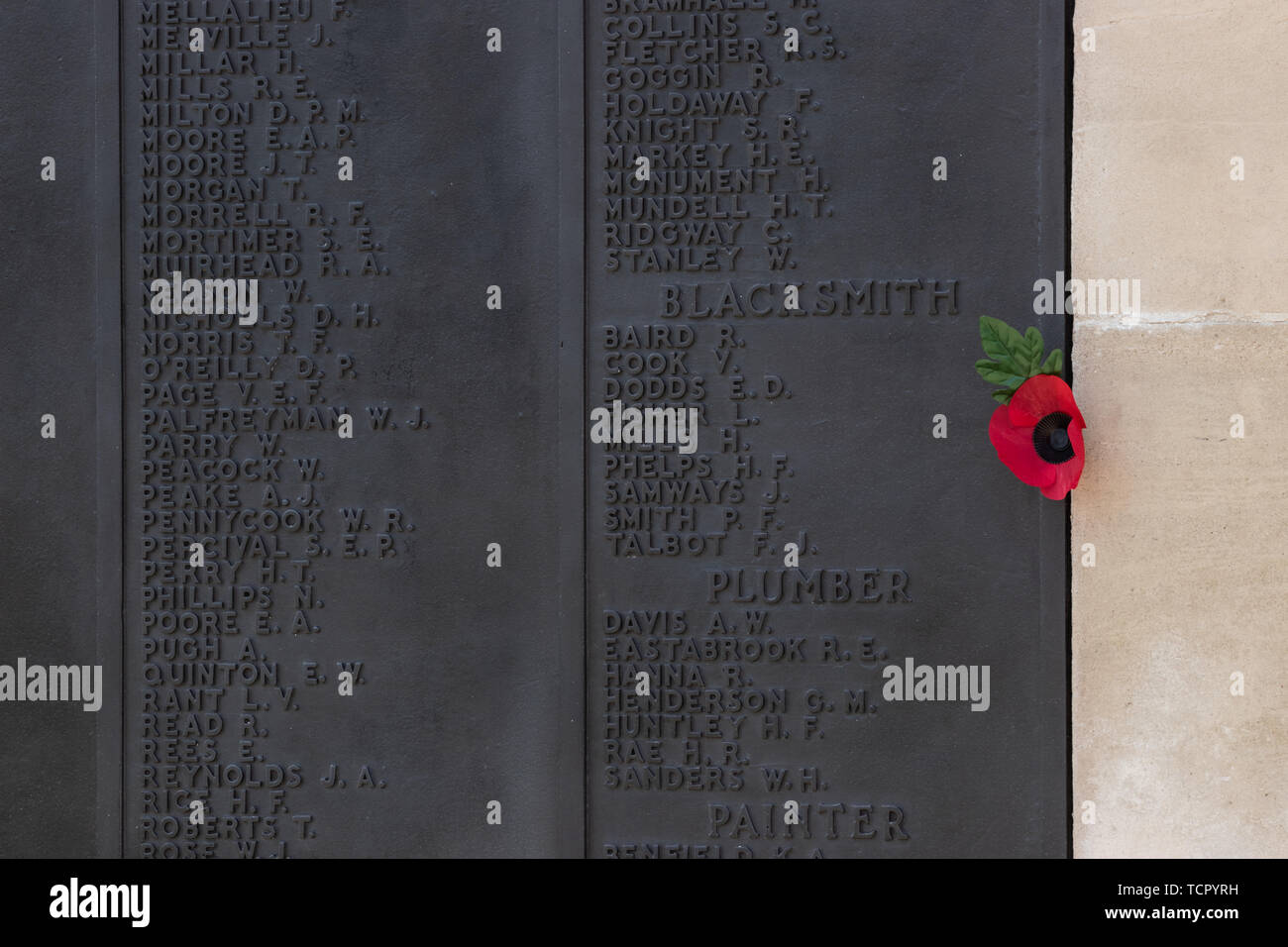 A single red poppy next to the names of the dead on a war memorial Stock Photo