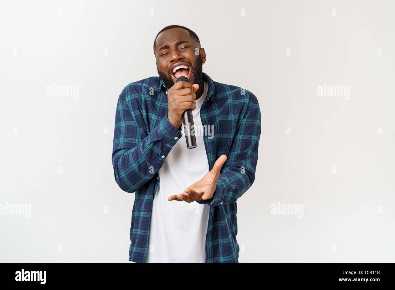 Portrait of cheerful positive chic handsome african man holding microphone  singing song. Isolated on white background Stock Photo - Alamy