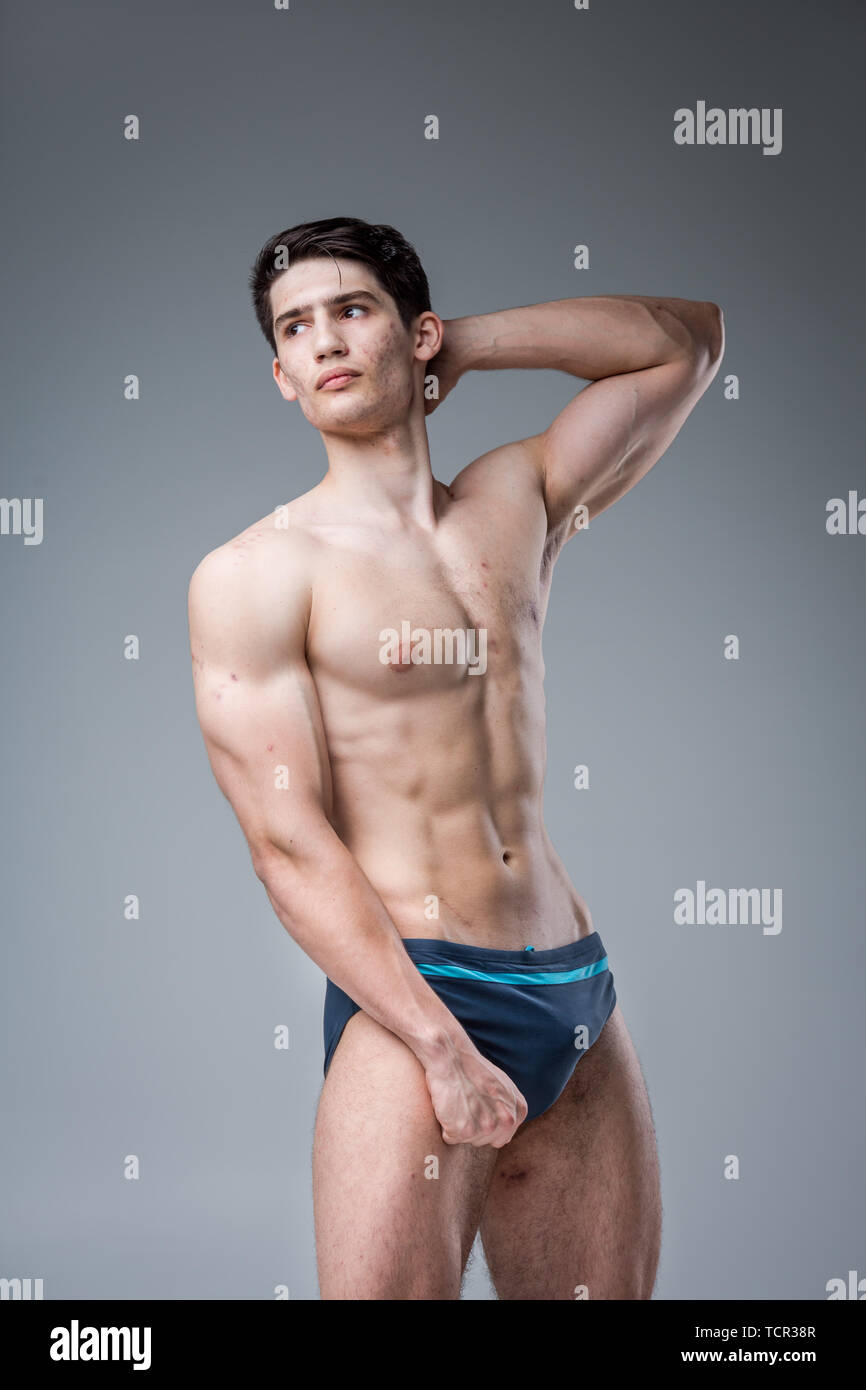 Studio portrait young Caucasian man on gray background posing. theme of puberty, problem skin, teen acne. Caucasian athlete fitness. Allergy sports nu Stock Photo