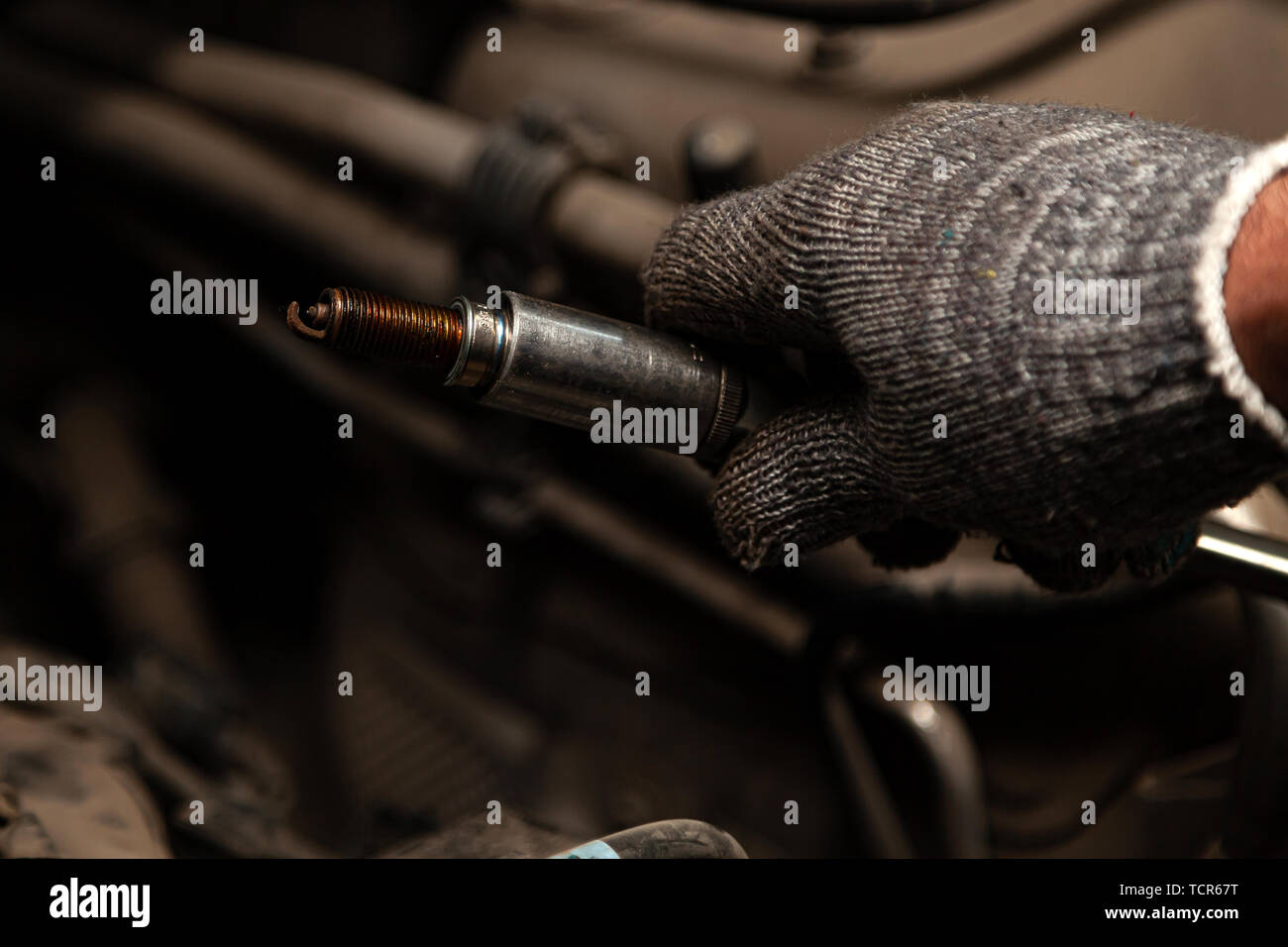 A serviceman repairs a car while replacing the spark plugs while