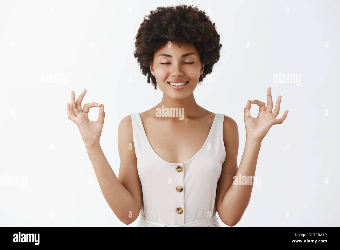 Keeping my mental health fit. Calm and relaxed good-looking happy, relieved African American woman in trendy clothes, closing eyes and smiling, holdin Stock Photo