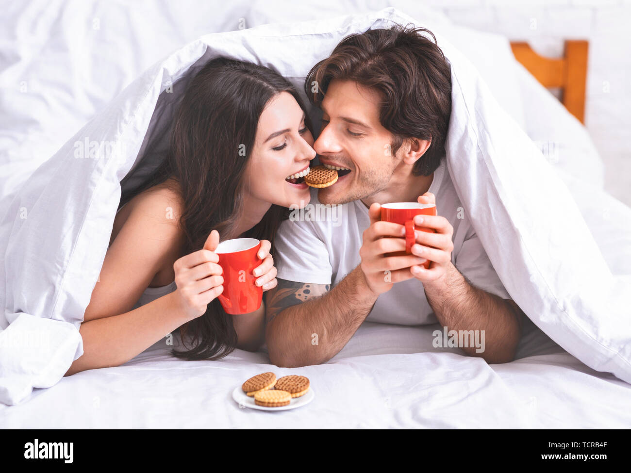 Cute millennial couple in love sharing breakfast in bed Stock Photo
