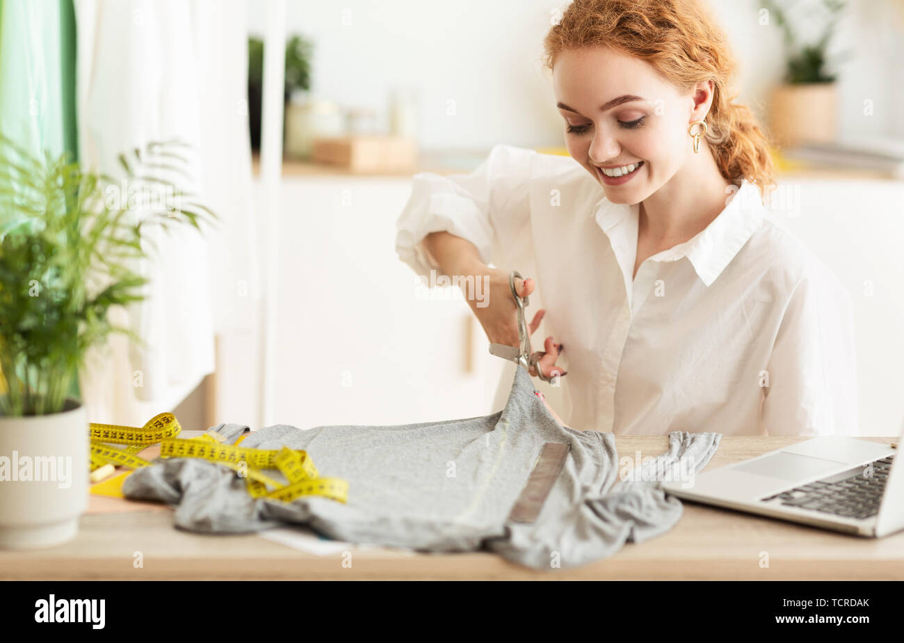 Fashion Designer Cutting Grey Fabric In Workshop Stock Photo