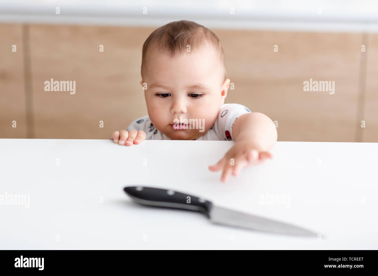 Dangerous situation in the kitchen. Child is trying to get a kitchen knife Stock Photo
