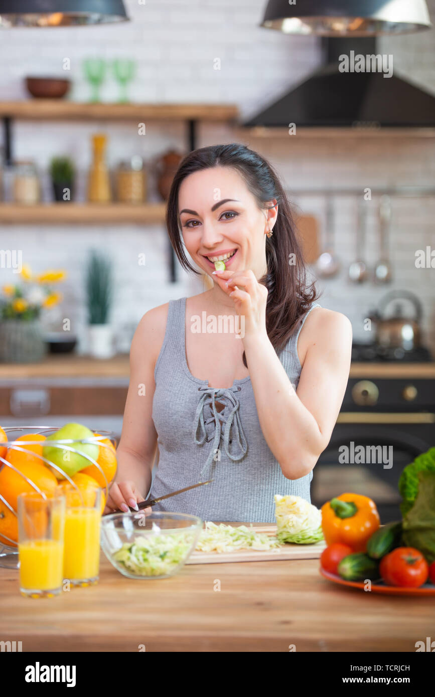 A hungry woman takes her hands and eats vegetables, stuffing them in
